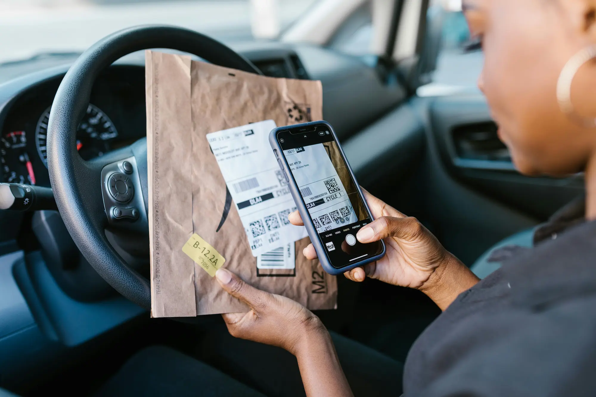 Delivery driver using app to scan package barcode in vehicle